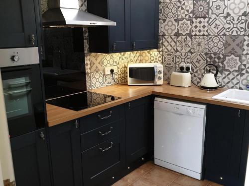 eine Küche mit schwarzen Schränken und einem weißen Gerät in der Unterkunft Fitling Cottage in Garton