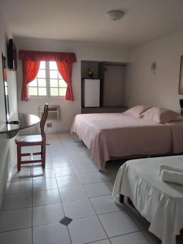 a bedroom with two beds and a table and a window at Viver Hotel Fazenda in Moreno