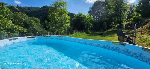 a man sitting in a chair next to a swimming pool at Le Temps Suspendu in Saint-Pierreville