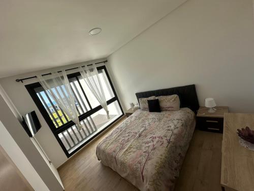 a bedroom with a bed and a large window at Prestigia plage des nations in Sale
