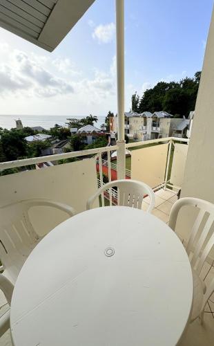 a white table and chairs on a balcony with the ocean at Sea view apartment, pool and beach 50m away in La Trinité