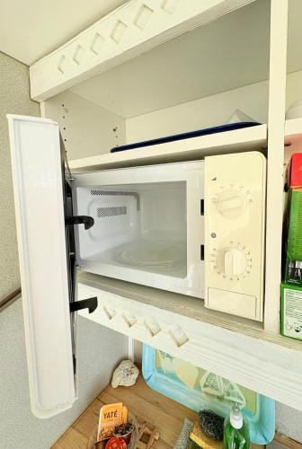 a white microwave in a refrigerator on a shelf at Sea view apartment, pool and beach 50m away in La Trinité