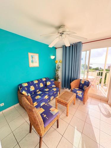 a living room with a couch and chairs and a table at Sea view apartment, pool and beach 50m away in La Trinité