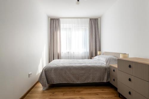 una camera da letto bianca con un letto e una finestra di Saulės laikrodžio apartamentai a Šiauliai