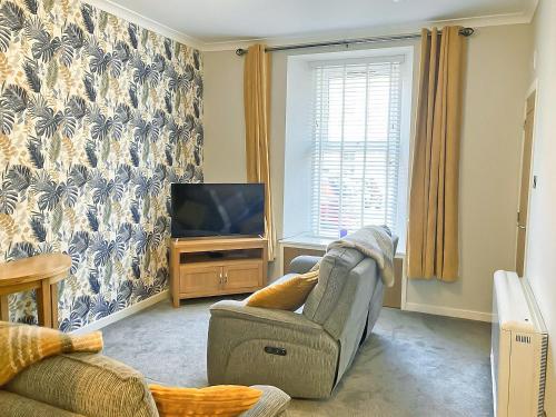 a living room with a chair and a television at The Wee Hideaway in Crieff