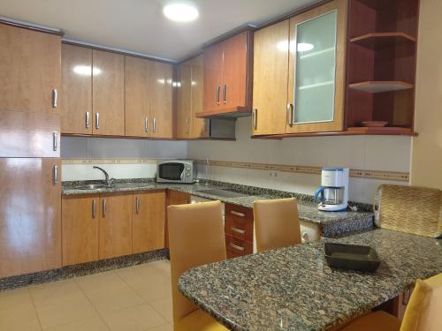 a kitchen with wooden cabinets and a counter top at Apartamentos As Caldelas in O Grove