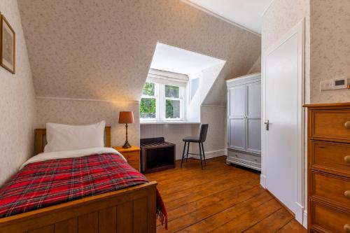 a bedroom with a bed and a desk and a window at St Andrews House in Fort William