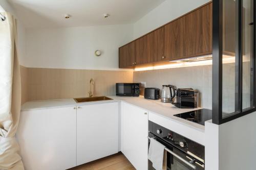une cuisine avec des armoires blanches et des appareils noirs dans l'établissement Magnifique studio boulevard gambetta - A, à Nice