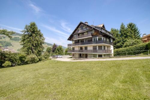 une grande maison sur une colline herbeuse avec une cour dans l'établissement Megève 4 seasons apartment, à Megève