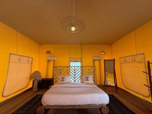 a bedroom with a bed in a yellow room at OKAÏ Oasis Desert Senegal in Lompoul