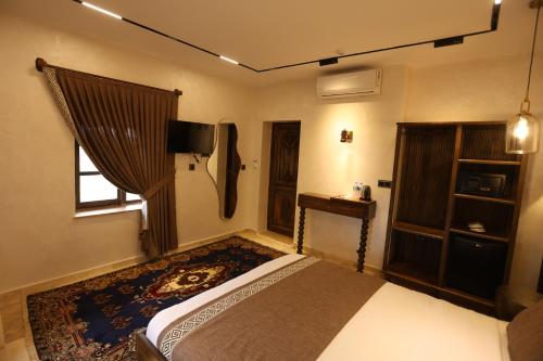 a bedroom with a bed and a tv and a window at Erdu Cappadocia Stone House in Avanos