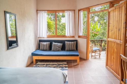 a bedroom with a blue bench in a room with windows at Venga Atitlan in San Marcos La Laguna