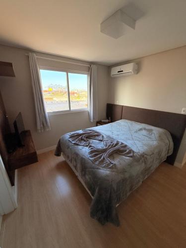 Un dormitorio con una cama y una ventana grande. en Exclusivity in Itajaí Port with Wi-Fi and Jacuzzi, en Itajaí