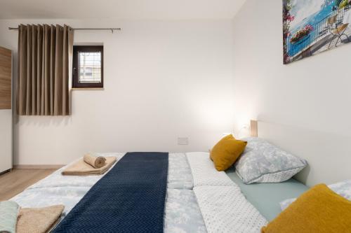 a bedroom with a large bed with yellow and blue pillows at Apartman Mistral in Funtana