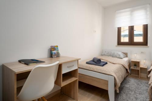a bedroom with a desk and a bed with a window at Apartman Mistral in Funtana