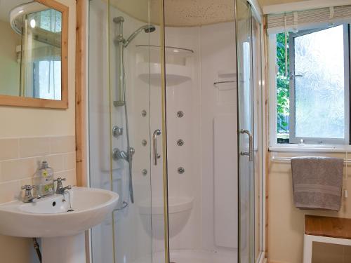 a bathroom with a glass shower and a sink at Drumble Lodge in Astbury