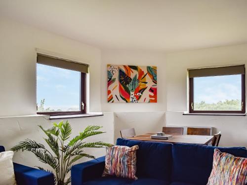 een woonkamer met blauwe banken en een tafel bij Sandymouth Cottage in Marhamchurch