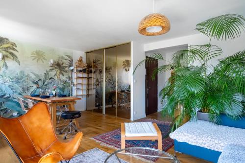 - un salon avec un canapé et des palmiers sur le mur dans l'établissement Spacieux appartement au calme proche de la mer, à Toulon