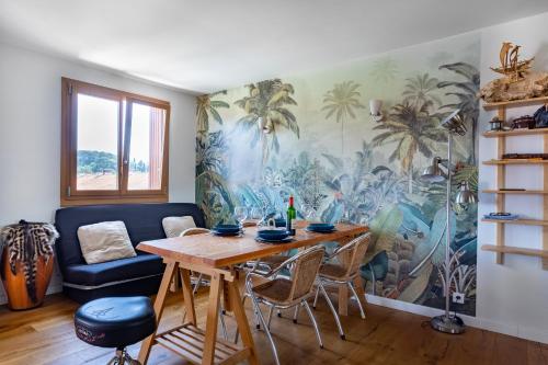 une salle à manger avec une table et une fresque murale de palmiers dans l'établissement Spacieux appartement au calme proche de la mer, à Toulon