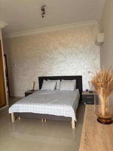 a bedroom with a bed with two night stands and two tables at Bel appartement avec piscine vue mer & golf in Asilah