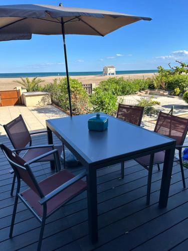 une table bleue et des chaises avec un parasol et la plage dans l'établissement Exclusive Beachfront Luxury!, à Gruissan
