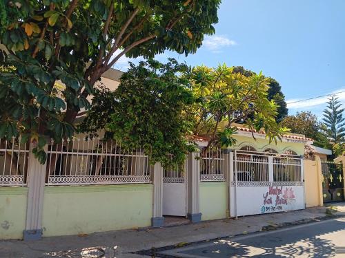 a fence in front of a house with trees at Hospedaje Las Flores Pedernales in Pedernales