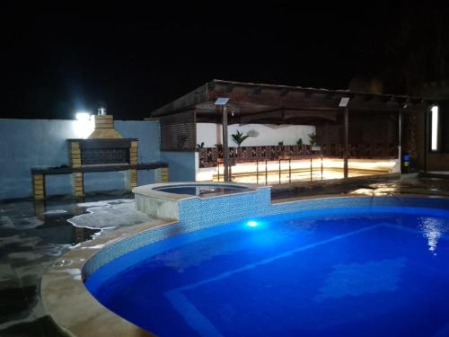 a blue swimming pool at night with a beach at Golden Horse Chalet And Club in Maḩaţţat al Jīzah