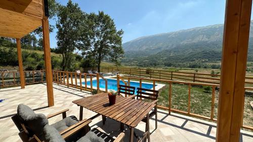 a patio with a wooden table and chairs and a pool at Green Oasis in Fshati i Ri
