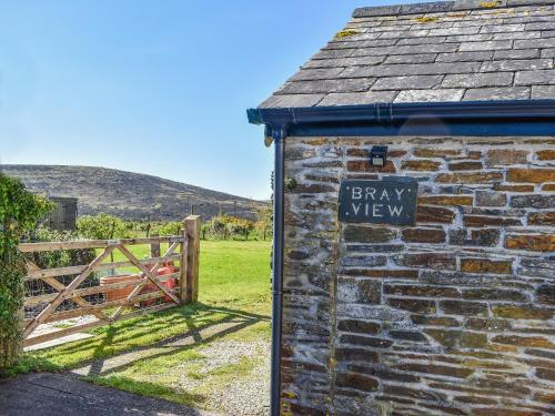 a brick building with a sign on it next to a gate at Bray View Cottage in Davidstow