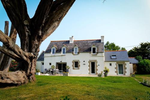 a large white house with a tree in the foreground at Ty Theven in Plouescat