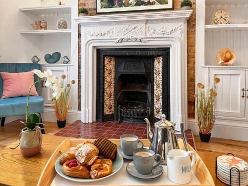 a table with a tray of pastries and a fireplace at The Anchor in Scarborough