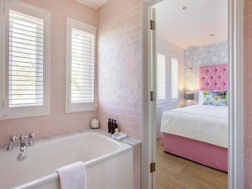 a pink bathroom with a tub and a bed at The Hedgehog-Uk46923 in Newby Bridge