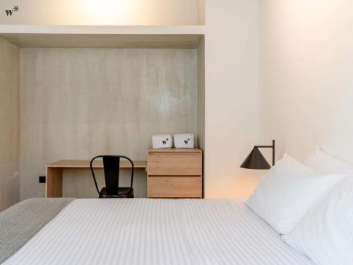a bedroom with a bed with a desk and a chair at Hotel Santa Ana Medellin in Medellín