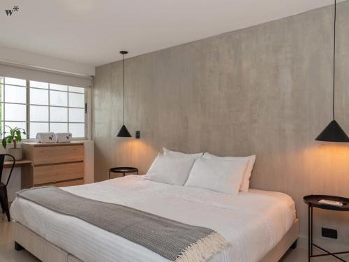 a bedroom with a large white bed and a wall at Hotel Santa Ana Medellin in Medellín