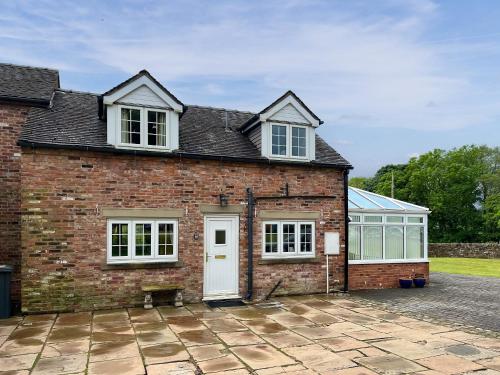 a brick house with a white door and windows at Netherhaye in Rudyard