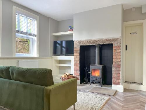 a living room with a couch and a fireplace at Rose Cottage in Cromford