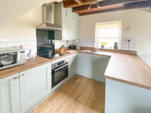 a kitchen with white cabinets and a wooden floor at Primrose Villa in Rosedale Abbey