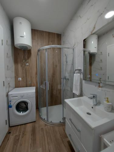 a bathroom with a shower and a washing machine at Apartman Nina Residence Banja Luka in Banja Luka
