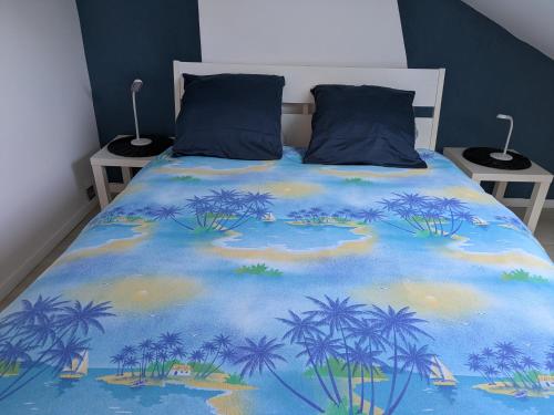 un lit avec une couverture bleue avec des palmiers dessus dans l'établissement Maisonlille, à Lille