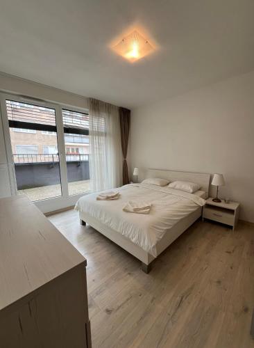a white bedroom with a bed and a large window at Elegant Escape Apartment I - City Centre & Free Parking in Bratislava