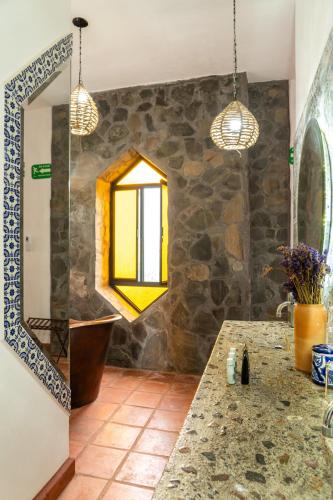 a bathroom with a mirror and a stone wall at Casa Trujillo in Capilla de Guadalupe
