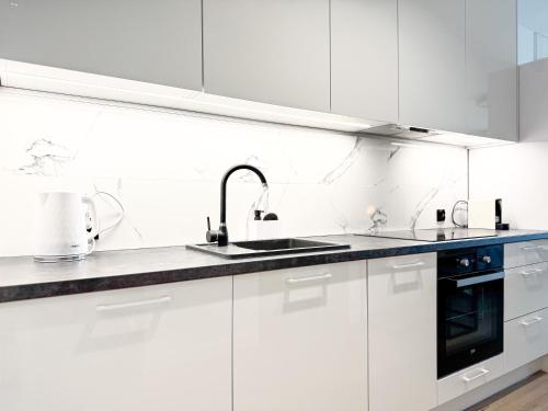 a white kitchen with white cabinets and a sink at Apartamenty Florina Q4Apartments in Łeba