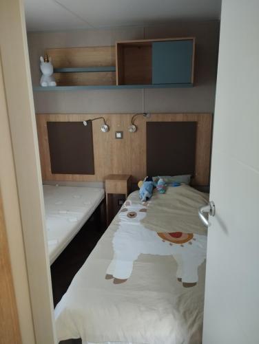 a room with a bed and a table with a stuffed animal at les sables du midi mobil home bougainvilliers in Sérignan