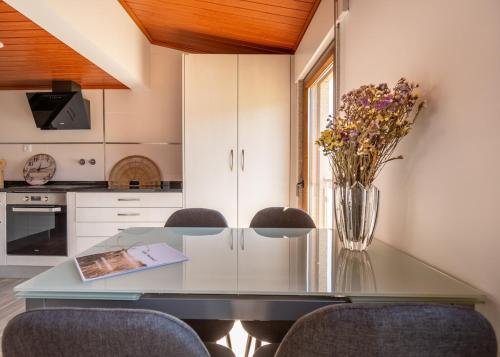 a kitchen with a glass table with a vase of flowers at Casa da Sertã in Sertã