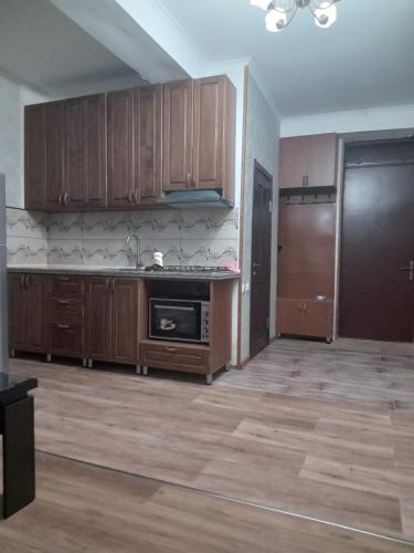une cuisine vide avec des placards en bois et une cuisinière dans l'établissement A cozy corner im Saburtalo 3, à Itʼkhvisi