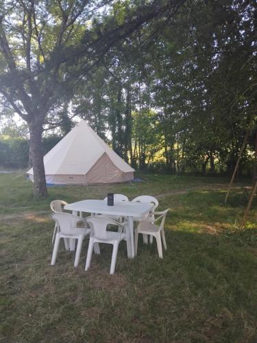 une table blanche et des chaises dans un champ avec une tente dans l'établissement Logement atypique, à Saint-Mesmin
