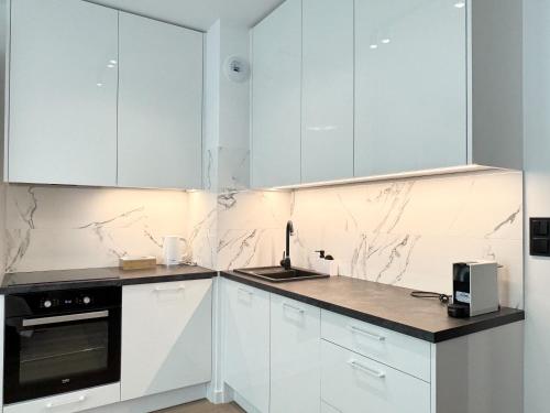 a kitchen with white cabinets and marble counter tops at Apartamenty Florina Q4Apartments in Łeba