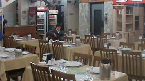 a man sitting at a table in a restaurant at Hekimoğlu Hotel in Erzurum