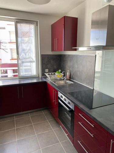 une cuisine avec des armoires rouges et un évier dans l'établissement Charmant T3 Vue Mer & Confort en Plein Centre, à Brest
