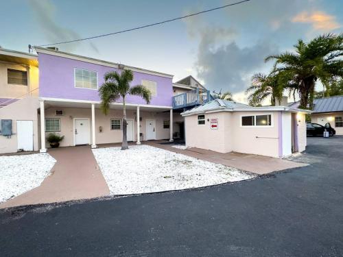 a purple house with a garage and palm trees at 1 King Bed Unit With Shared Pool in Clearwater